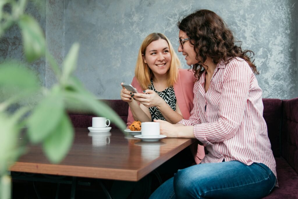 Two women enjoying a conversation over coffee and cupcakes in a cozy cafe setting.